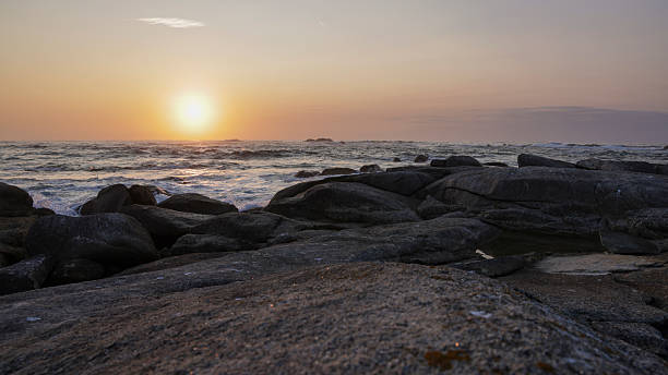 istock The sun is setting over the ocean, casting a warm glow over the rocky shore 2235911353