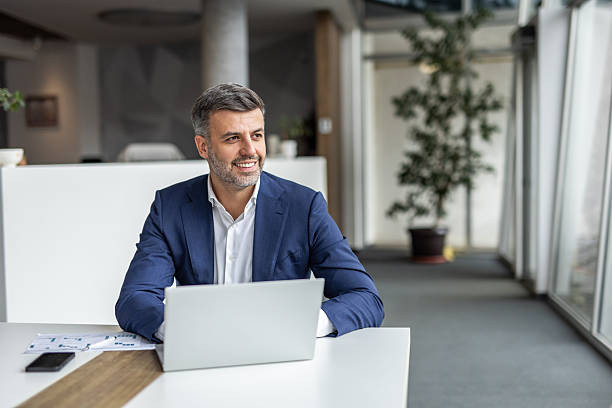 istock Smiling businessman working on laptop in modern office 2235913124