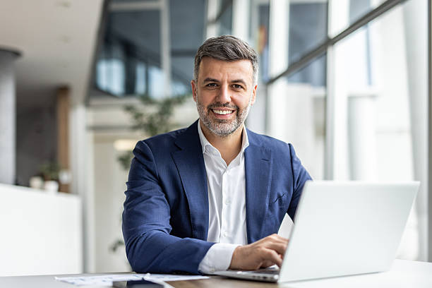 istock Smiling businessman working on laptop in modern office 2235913132
