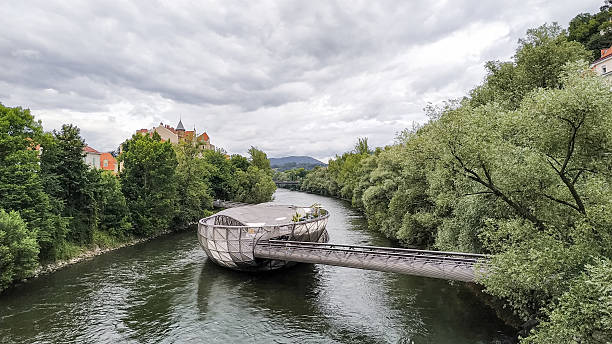 Graz, Austria - December 16, 2010: Graz cityscape with Murinsel in foreground, the modern building designed by New York artist Vito Acconci when Graz became the Cultural Capital of Europe for 2003. It houses a cafe and an amphitheater.