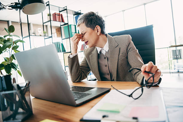 istock Senior professional in stylish attire experiencing stress while working at her office desk with a laptop 2235917626