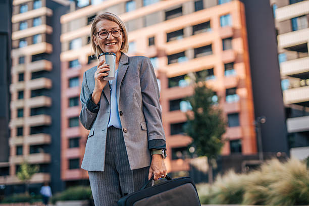 Smiling businesswoman drinking coffee outdoors in urban setting