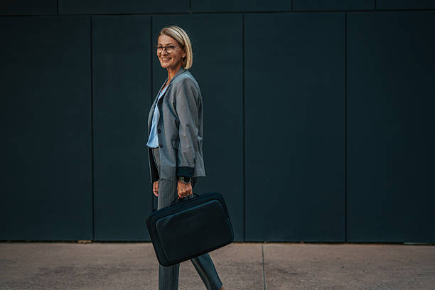 istock Smiling businesswoman walking with briefcase in urban setting 2235920162