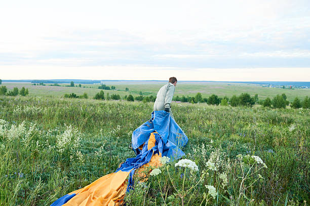 istock Young Caucasian Man Walking through Meadow Carrying Paragliding Equipment 2235922028