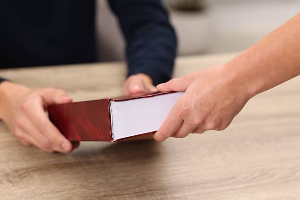 Writer signing book for reader at wooden table, closeup