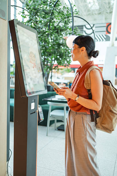 istock Young woman ordering food using digital self-service kiosk in restaurant 2235924454
