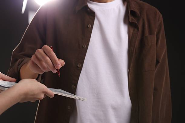 Man signing autograph in notebook on dark background, closeup