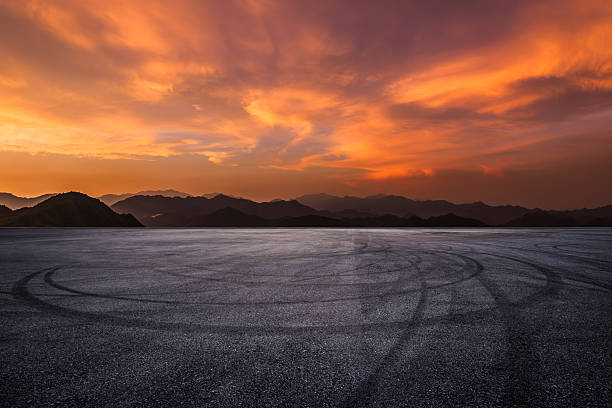 istock Empty asphalt race track with tire marks and beautiful mountain silhouette under a dramatic sunset sky 2235926509