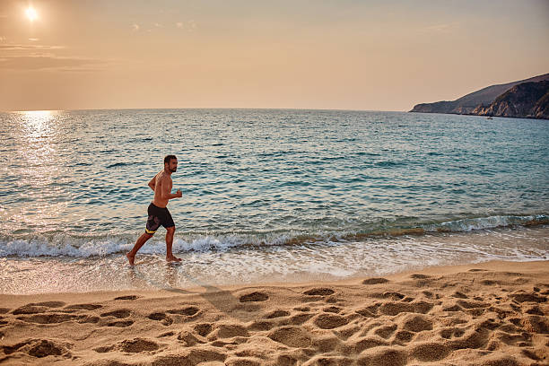 Man running on a tropical beach during sunrise.