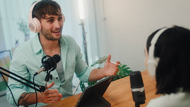 istock Generation Z podcasters collaborating wearing headphones discussing topics during recording session together in home studio. 2235930613
