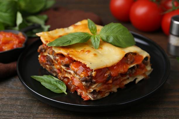 istock Delicious cooked lasagna with basil on wooden table, closeup 2235932311