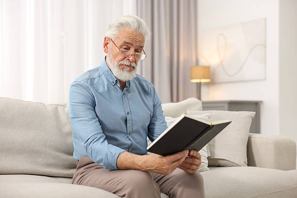 istock Handsome bearded man reading book on sofa indoors 2235933145