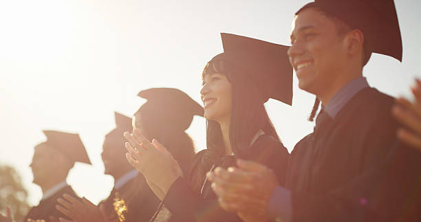 istock Clapping, education and graduation with students outdoor for celebration, milestone or success. Achievement, applause and scholarship with graduate people, excited on college on university campus 2235933720