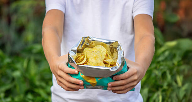 istock Boy eating chips from a pack. Unhealthy food concept 2235935181