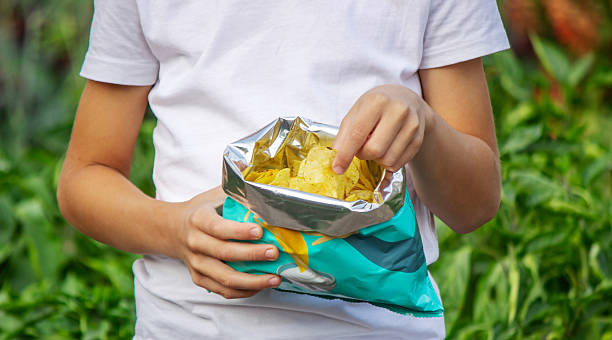 istock Boy eating chips from a pack. Unhealthy food concept 2235935183