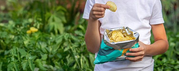 istock Boy eating chips from a pack. Unhealthy food concept 2235935184
