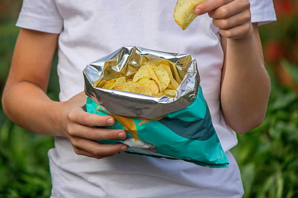 istock Boy eating chips from a pack. Unhealthy food concept 2235935185