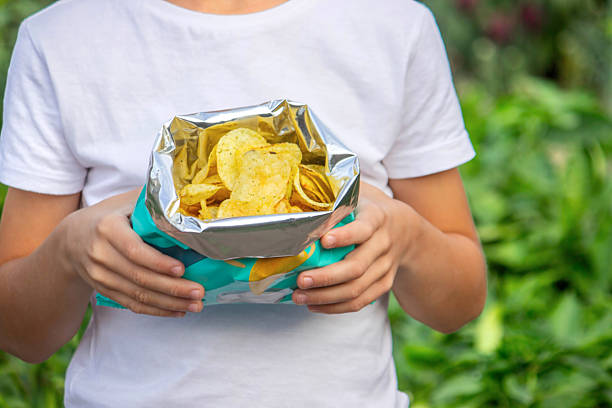 istock Boy eating chips from a pack. Unhealthy food concept 2235935187