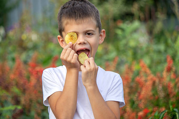 istock Boy eating chips from a pack. Unhealthy food concept 2235935214