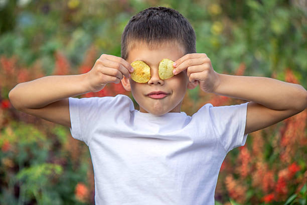 istock Boy eating chips from a pack. Unhealthy food concept 2235935215