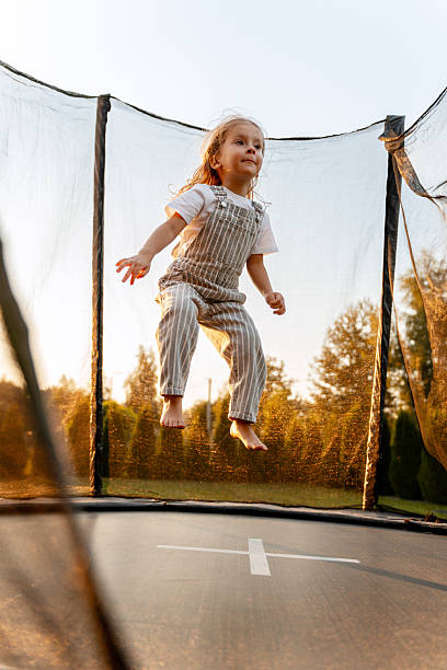 istock Little girl jumping on trampoline at sunset having fun 2235935574