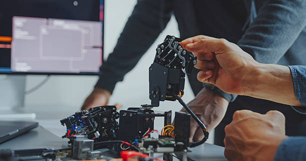 istock Closeup of Black and Hispanic male engineers programmers work together on robot hand prototype, use computer control robotic arm circuit in tech office. Software developer, artificial intelligence. 2235936362