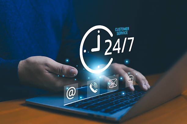 istock Businessman using laptop with glowing 24/7 customer service icons including email, phone, chat, symbolizing online support, client assistance, communication, reliability, and round-the-clock service. 2235938206