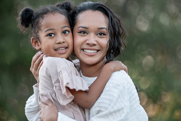 istock Smiling Mother Embraces Her Young Daughter Outdoors in Natural Sunlight 2235942050