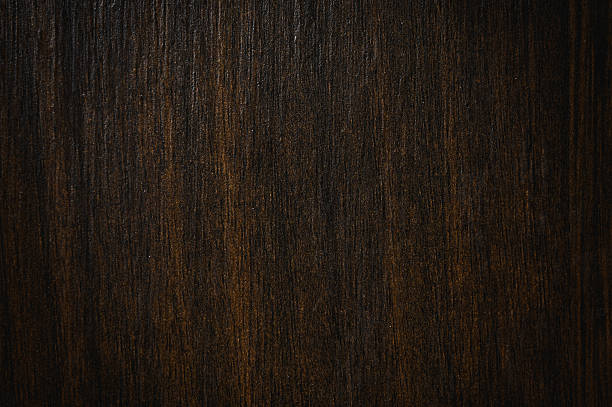 Dark brown wood grain texture background showing growth rings