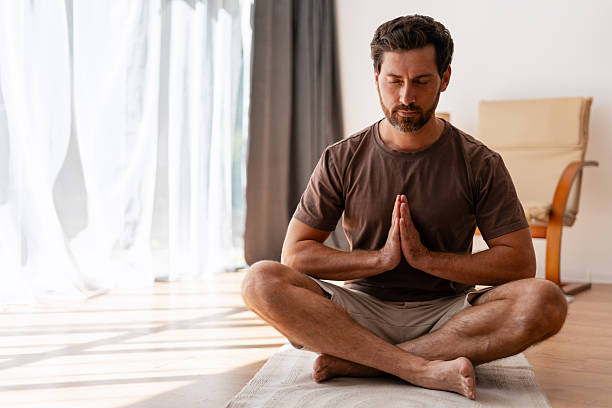 istock Man practicing yoga and meditating at home in the morning 2235944908