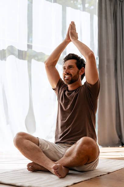 istock Man practicing yoga, meditating in lotus position at home 2235944931