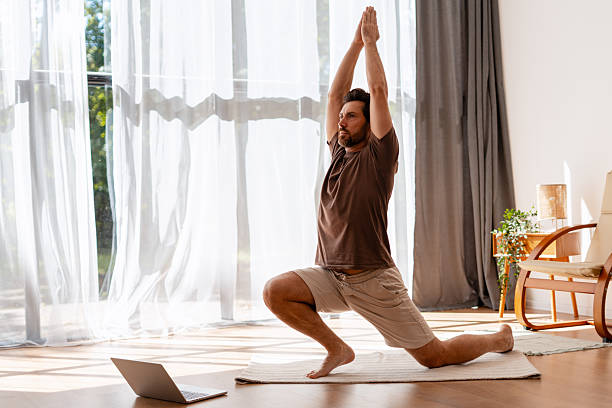 istock Man practicing yoga at home using laptop for online class 2235944966