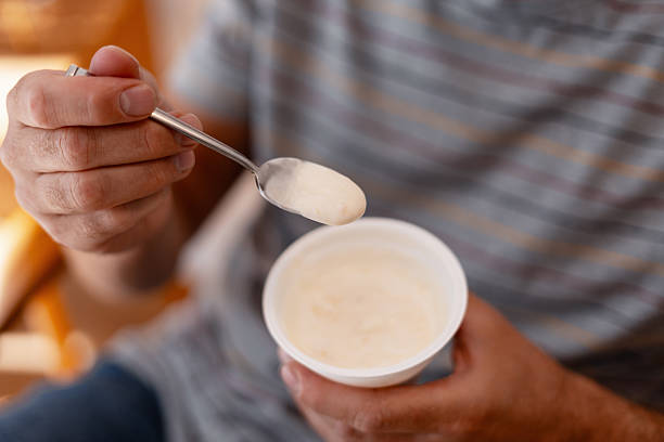 istock Man eating yogurt with a spoon from a plastic cup 2235945133