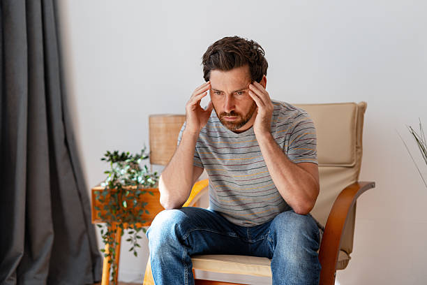 istock Stressed man suffering from headache, touching temples, sitting at home 2235947150