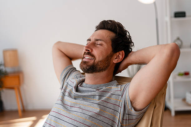 istock Man relaxing on chair with hands behind head at home 2235947807