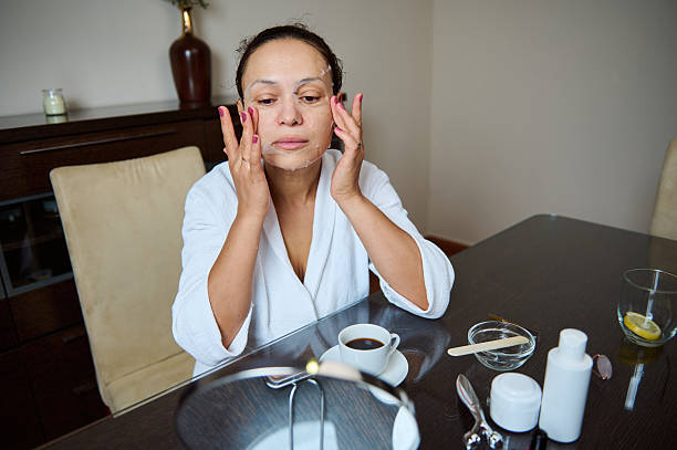 istock Woman Applying a Skincare Mask While Sitting at a Table Reflectively 2235948464