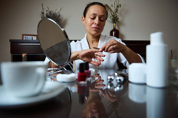 istock Woman in Bathrobe Performing Hand Care Routine with Mirror and Nail Tools 2235949131