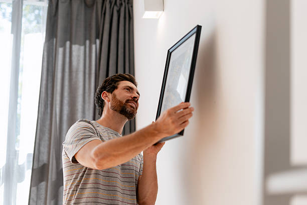 istock Man Hanging a Picture Frame on the Wall at Home 2235949181