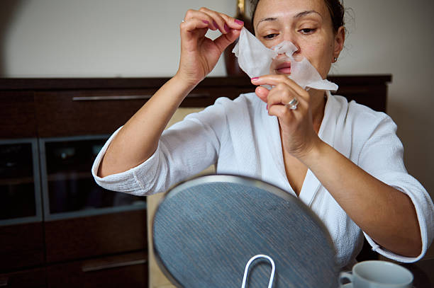 istock Woman Removing Face Mask While Sitting at a Vanity Mirror 2235949559