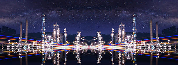 istock reflection image an illuminated industrial plant at night, reflected on the water's surface below. Light trails from vehicles and a starry sky complete the scene, blending technology with nature. 2235950550