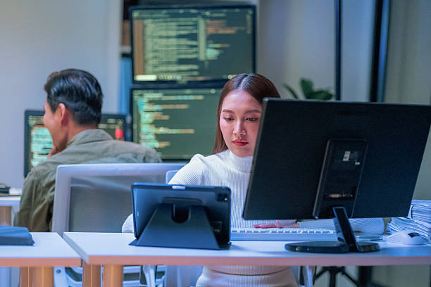 istock young Asian software development manager leads a late-night office discussion with his executive team, mentoring developers and analyzing source code to guide programming and project development 2235950569
