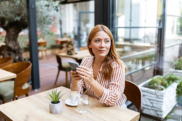 istock Attractive young woman enjoying coffee while browsing phone 2235952353