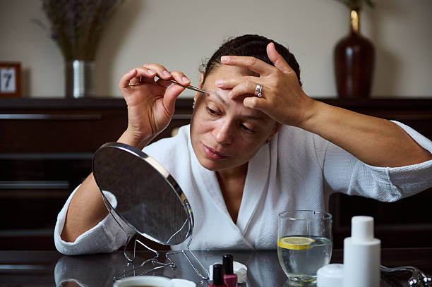 istock Woman Grooming Eyebrows with Tweezer in Bathroom Vanity Routine 2235953790