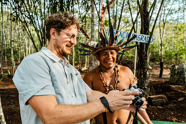 Visitor demonstrates connection moment showing photographic records to Curripaco community member wearing traditional headdress, promoting genuine exchange through technology and creating respectful cultural bridge during ethnic tourism experience in Amazonian village