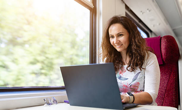 istock Young Caucasian woman smiling while working on laptop during train travel 2235955504