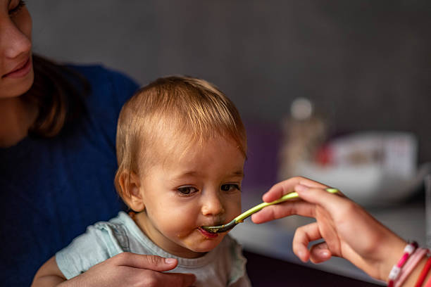 istock Mother feeding her baby solid food with a spoon 2235955598