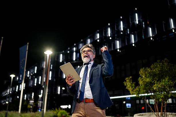 istock Excited businessman celebrating success while holding digital tablet at night 2235955649