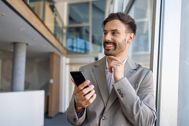 istock Smiling businessman using smartphone in modern office building 2235956699