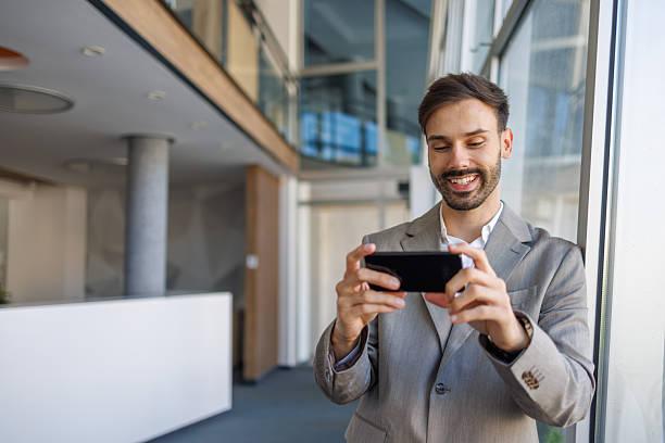 istock Young businessman taking photos with smartphone in modern office 2235956710