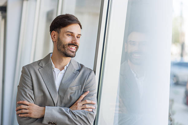 istock Smiling businessman looking out of office window 2235956736